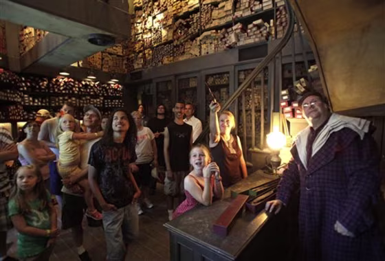 A&nbsp;clerk, right, at Ollivander's Wand Shop helps visitors pick out a magic wand June 9 at The Wizarding World of Harry Potter at Universal Orlando in Orlando, Fla.&nbsp;In the quarter after the attraction opened, crowds at Universal parks swelled by 36 percent over the same stretch last year, while attendance at Disney's Orlando parks stayed roughly the same.